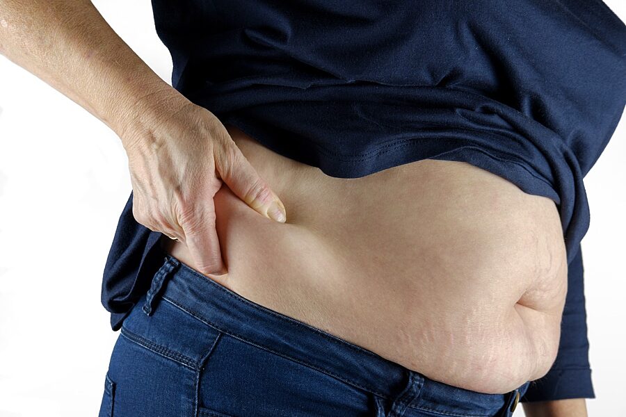 A person's hand pinching the side of their belly